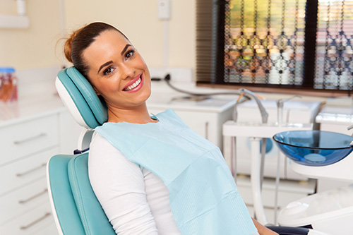 woman sitting in a dentist chair smiling and ready for her procedure